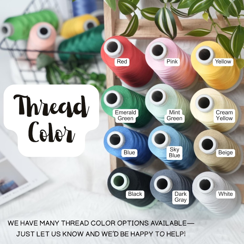 May include: A display of colorful thread spools in various shades, including red, pink, yellow, and green. The image features a wooden rack with labeled thread colors, such as "Blue," "Black," and "White." The text "Thread Color" is also visible.