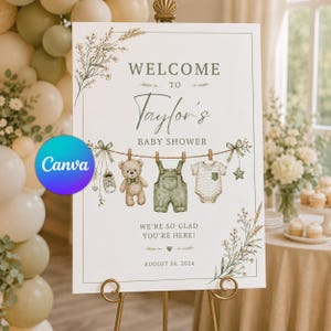 Może przedstawiać: Biały prostokątny znak powitalny na baby shower z napisem Welcome to Taylor's Baby Shower. Projekt zawiera ilustracje pluszowego misia, zielonych ogrodniczek, body w paski oraz dziecięcych bucików zawieszonych na sznurku do prania.