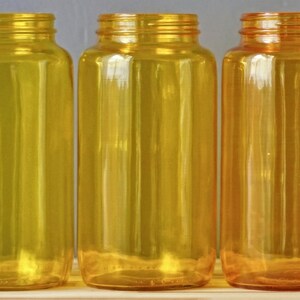 May include: Three amber glass bottles with a clear, slightly textured surface. The bottles are empty and have a cylindrical shape.