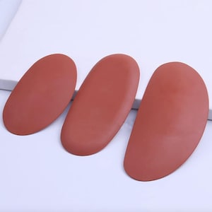 May include: Three terracotta-coloured clay ribs or pottery scrapers with smooth, rounded edges. These tools feature a solid, matte finish and are shaped with varying degrees of curvature, designed for shaping and smoothing clay surfaces during pottery work.