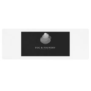 Puede incluir: Una alfombra rectangular blanca con un rectángulo negro en el centro. El rectángulo negro presenta un logotipo en escala de grises con el texto "FOG & FOUNDRY" y un diseño apilado y en capas. El texto "SAN FRANCISCO EST. 2020" está debajo.