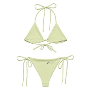 Peut inclure: Un ensemble bikini vert lime clair composé d'un haut triangle avec des liens à nouer au cou et dans le dos. Le bas assorti présente des liens latéraux et un petit logo gris sur la hanche gauche indiquant FOG & FOUNDRY en lettres droites.