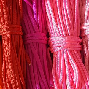 May include: A collection of colorful elastic cords, arranged in rows, showcasing a variety of vibrant hues, including blue, green, yellow, orange, red, pink, purple, light blue, beige, and brown.