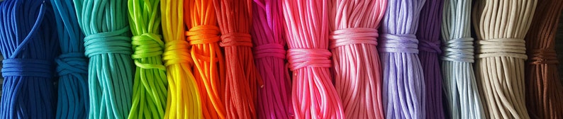 May include: A collection of colorful elastic cords, arranged in rows, showcasing a variety of vibrant hues, including blue, green, yellow, orange, red, pink, purple, light blue, beige, and brown.