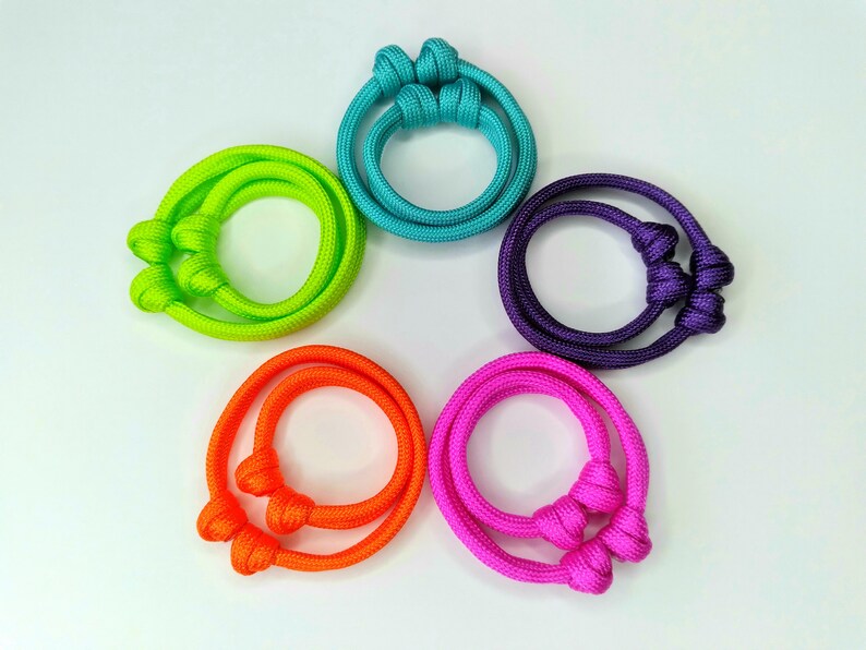 May include: Five colorful bracelets made of knotted rope. The bracelets are in shades of turquoise, lime green, purple, orange, and pink.