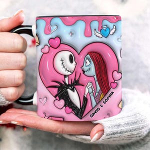 May include: A ceramic mug featuring Jack Skellington and Sally from The Nightmare Before Christmas, set within a pink heart. The mug has a black handle and rim, with the names "DAVID & SOPHIA" printed on the side. The design includes pink and blue accents.
