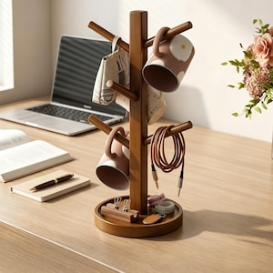 May include: A vertical wooden tree-shaped organizer stand with a round base. The stand features multiple branches holding two ceramic mugs with egg patterns, a small fabric pouch, and a coiled brown charging cable. The base holds small office items.
