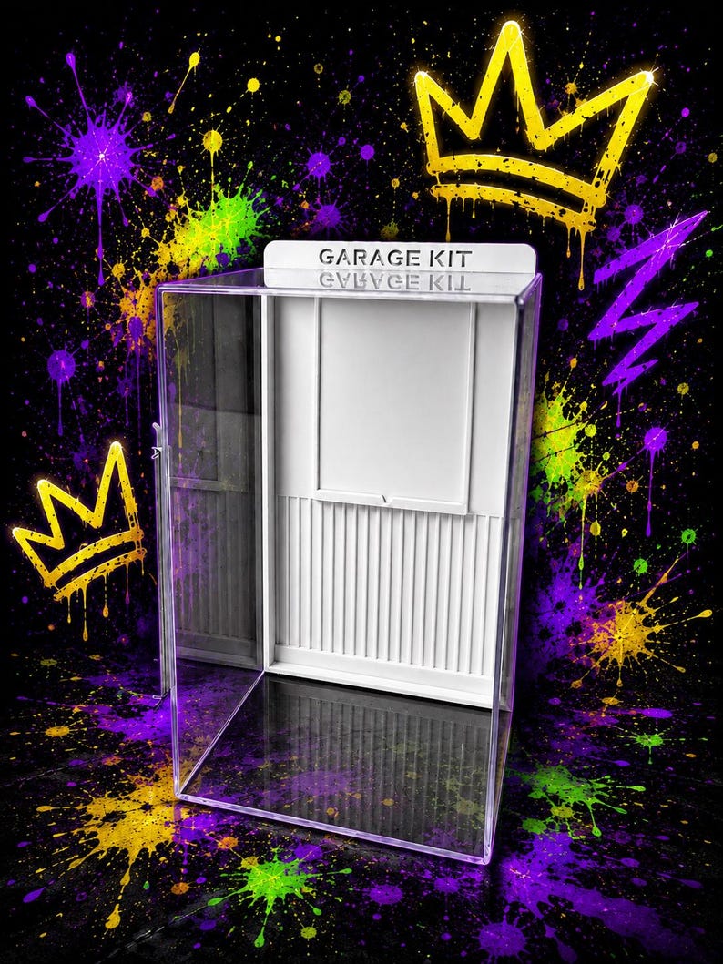 K&ouml;nnte beinhalten: Eine transparente Acryl-Vitrine mit einer wei&szlig;en Innenr&uuml;ckwand, die vertikale Lamellen und einen rechteckigen Rahmen aufweist. Die Kopfleiste ist mit dem schwarzen Schriftzug GARAGE KIT versehen. Das Geh&auml;use steht vor einem schwarzen Hintergrund.