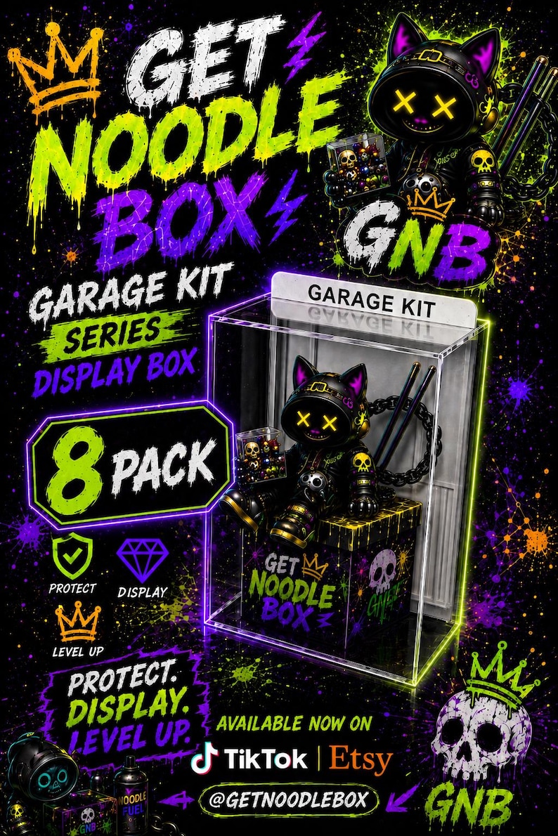 K&ouml;nnte beinhalten: Eine durchsichtige Acryl-Vitrine f&uuml;r eine Garage-Kit-Serie mit einer schwarzen Katzenfigur, die gelbe X-f&ouml;rmige Augen, eine Krone und Totenkopfmotive aufweist. Die Box ist mit den Schriftz&uuml;gen GARAGE KIT und GET NOODLE BOX sowie neonfarbenen Spritzern versehen.