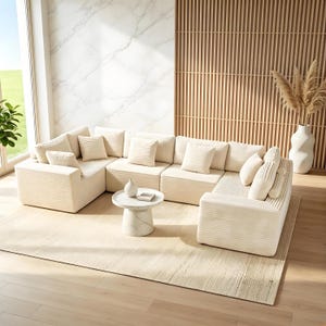 May include: A modular cream-colored corduroy sectional sofa with matching throw pillows. The sofa is arranged in an L-shape on a cream rug. A small marble side table and a white vase with decorative grasses are also present.