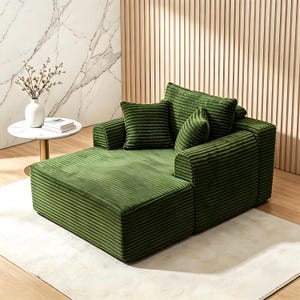 May include: A green corduroy sectional sofa with a chaise lounge. The sofa has a boxy design with thick, ribbed fabric. Several matching square and cylindrical pillows are arranged on the back. A small, round side table with a white top and gold base is in the background.