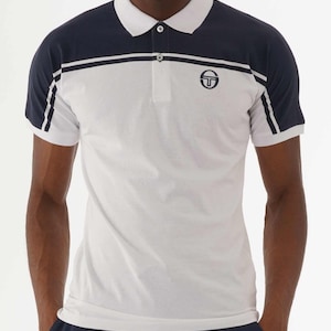 May include: White and navy blue polo shirt with a white collar and a three-button placket. The shirt features a navy blue upper section and sleeves with white stripes, and a logo on the chest. A classic, sporty design.