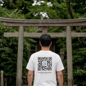 May include: A white short-sleeved t-shirt featuring a black and white QR code on the back. The center of the QR code contains the letters DS in a light blue square. Below the code is the text Your daily haiku awaits and DailyScanCompany.com.