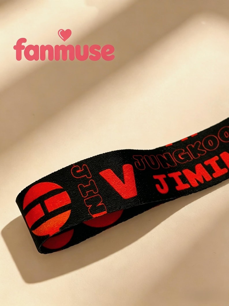 May include: Black lanyard with red text and design elements. The text includes the names "JUNGKOO", "JIMIN", and "JIN", along with a large red "V". The lanyard also features red circular designs.