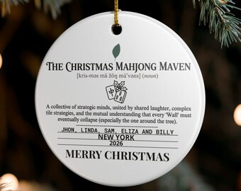 May include: A round white ceramic Christmas ornament hanging by a gold string. It features black text reading The Christmas Mahjong Maven, a definition, a mahjong tile graphic, names Jhon, Linda, Sam, Eliza and Billy, New York, 2026, and Merry Christmas.