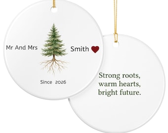 May include: Two round white ceramic ornaments with gold hanging strings. One features a green pine tree with roots, the text Mr And Mrs Smith, a red heart, and Since 2026. The other displays the text Strong roots, warm hearts, bright future.