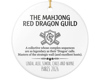 May include: A round white ceramic ornament with a gold hanging string. It features the black text THE MAHJONG RED DRAGON GUILD, a dragon shield emblem, descriptive text about the guild, and the names LINDA, ALEX, SIMON, CHRIS AND WAYNE PARIS 2026.