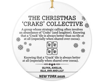 May include: A round white ceramic ornament with a gold hanging string. It features black text reading THE CHRISTMAS 'CRAKS' COLLECTIVE, a description of a group, four mahjong tiles, the names OLIVIA, AMELIA, ISLA, AVA AND LILY, and NEW YORK 2026.