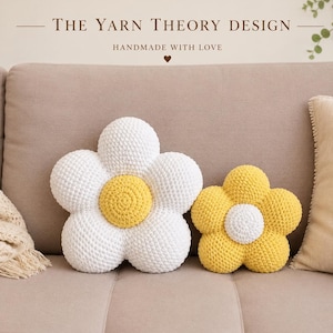 May include: Two flower-shaped crochet pillows. The larger pillow has white petals and a yellow center. The smaller pillow has yellow petals and a white center. Text above reads: THE YARN THEORY DESIGN HANDMADE WITH LOVE.