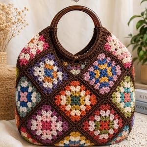 May include: A crochet tote bag featuring a pattern of multi-colored granny squares joined by dark brown yarn. The bag has two round, dark brown, polished handles. Text on the image reads: THE YARN THEORY DESIGN, CROCHET, HANDMADE, TIMELESS, FINISHED PRODUCT, Colorful Granny Square Tote Bag.