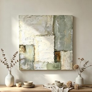 Pode incluir: Uma pintura abstrata quadrada com camadas espessas e texturizadas de empaste em tons de verde sálvia, creme, branco e castanho terroso. A composição consiste em blocos geométricos de cor com pinceladas visíveis e superfícies em relevo.