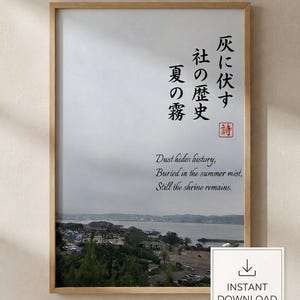 以下が含まれることがあります： 曇り空の下の海岸風景を写した写真の額入りアートプリント。プリントには日本語の書道と英語のテキスト「Dust hides history, Buried in the summer mist, Still the shrine remains.」が記載されています。