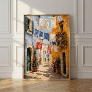 May include: An oil painting depicting a narrow Mediterranean street scene with laundry hanging on lines between a blue building and a yellow building. Potted flowers sit by arched doorways, and a small balcony with red flowers is visible.