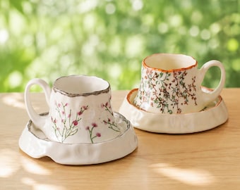 Juego de taza y platillo de cerámica con diseño floral pintado a mano, estilo cottagecore botánico.