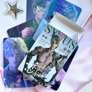 Può includere: Una collezione di carte collezionabili rettangolari con personaggi maschili in stile anime dai capelli argentati. Una carta mostra un personaggio a torso nudo con armatura, con il testo SYUS, QINCHE e Exchange half souls, share life and death together.