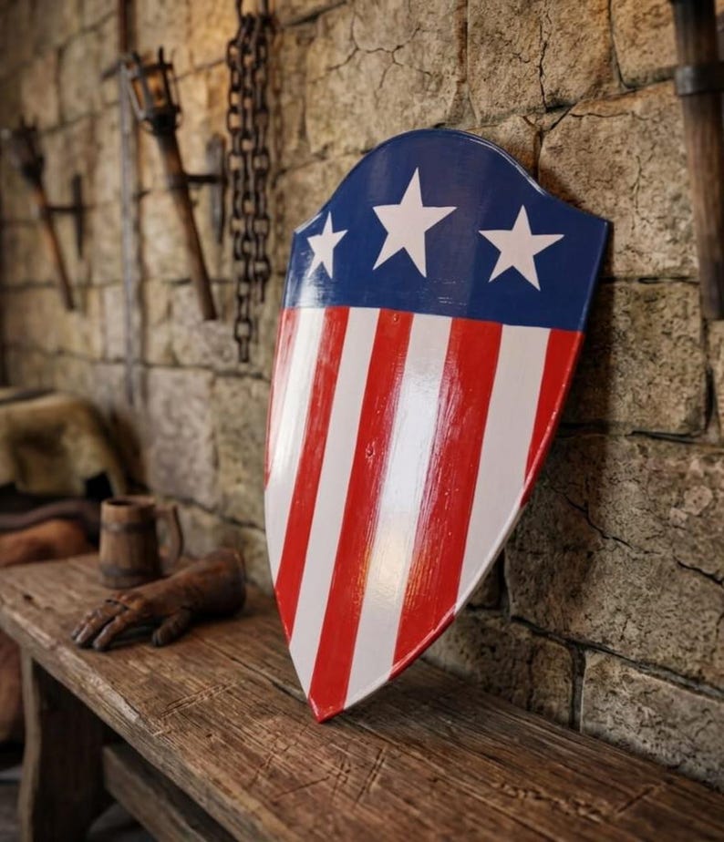 May include: A heater-style shield featuring a glossy finish with a blue upper section adorned with three white five-pointed stars, and a lower section displaying vertical red and white stripes. The shield has a pointed base and curved top edges.