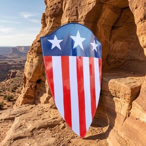 May include: A pointed shield featuring a glossy finish with a dark blue upper section containing three white five-pointed stars, and a lower section with alternating vertical red and white stripes. The shield has a smooth, curved surface.
