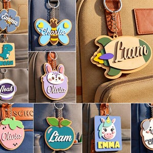 Peut inclure: Un ensemble de dix étiquettes de sac en bois découpées au laser représentant diverses formes comme une fusée, un papillon, une fraise, une pomme, un dinosaure et une licorne. Chaque étiquette porte un nom personnalisé attaché à un anneau.