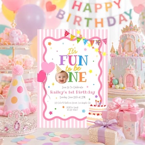 Op de afbeelding: Een rechthoekige verjaardagsuitnodiging met een roze en wit gestreepte achtergrond, voorzien van een babyfoto, kleurrijke vlaggetjes en de tekst It's FUN to be ONE, Railey's 1st Birthday, Sunday, June 15th at 2PM, 123 Colorful Balloon Street, Los Angeles, CA.