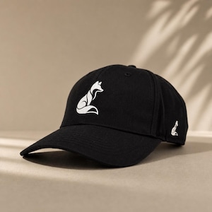 Pode incluir: Bon&eacute; de beisebol preto com um desenho de raposa branca na frente e um logotipo de raposa menor na lateral. O bon&eacute; tem uma aba curva e um design cl&aacute;ssico ajust&aacute;vel.