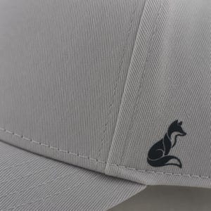 Pode incluir: Bon&eacute; de beisebol cinza claro com um logotipo de raposa preta na lateral. O bon&eacute; tem um design estruturado com costuras vis&iacute;veis e uma aba curva. O tecido tem uma textura vertical sutil.