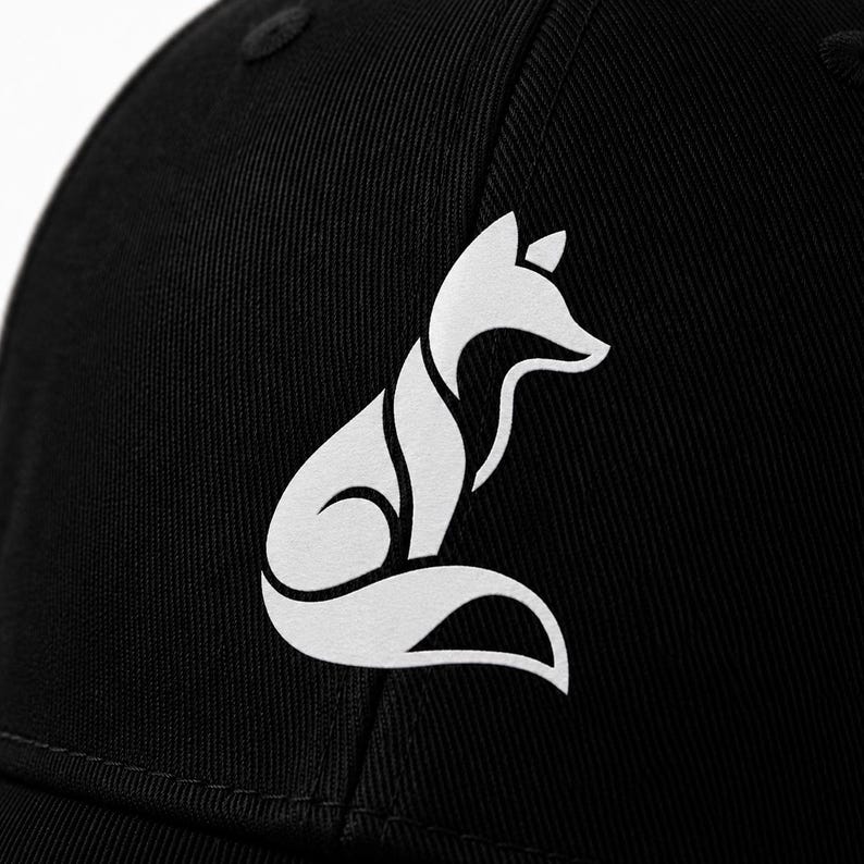 Pode incluir: Bon&eacute; de beisebol preto com um logotipo de raposa branca estilizado. O design da raposa &eacute; uma ilustra&ccedil;&atilde;o minimalista e geom&eacute;trica. O bon&eacute; tem uma aba curva e um bot&atilde;o na parte superior. Feito de tecido dur&aacute;vel.