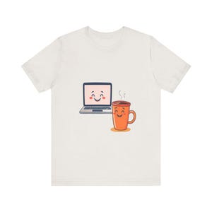 Könnte beinhalten: Weißes T-Shirt mit einem Cartoon-Design eines lächelnden Laptops und einer Kaffeetasse. Der Laptop ist grau und die Tasse ist orange mit aufsteigendem Dampf. Das Design ist mittig auf dem T-Shirt platziert.