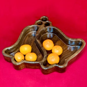 May include: A wooden bowl shaped like two bells, filled with six small orange clementines.