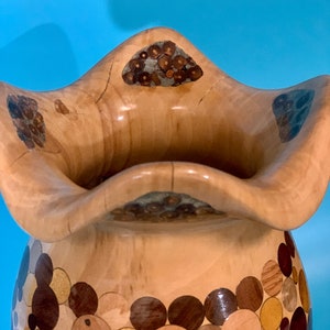 Puede incluir: Un jarr&oacute;n de madera con un dise&ntilde;o &uacute;nico. El jarr&oacute;n est&aacute; hecho de varias piezas de madera, cada una con un color y una veta diferentes. El jarr&oacute;n tiene una boca ancha y una base estrecha. El jarr&oacute;n es una hermosa y &uacute;nica obra de arte.