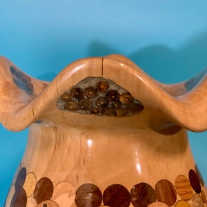 Puede incluir: Un jarr&oacute;n de madera con un dise&ntilde;o &uacute;nico. El jarr&oacute;n est&aacute; hecho de diferentes tipos de madera, creando un patr&oacute;n de mosaico. La parte superior del jarr&oacute;n tiene un borde ondulado y festoneado.