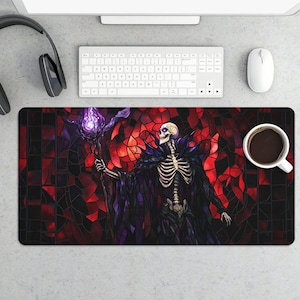 May include: A rectangular mousepad featuring a skeletal figure in a dark cloak, holding a staff with a purple flame. The background is a stained-glass design in red and black. A white keyboard, mouse, and coffee cup are visible.
