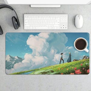 K&ouml;nnte beinhalten: Rechteckiges Mauspad mit einer lebendigen Illustration eines grasbewachsenen H&uuml;gels mit Blumen, blauem Himmel und zwei Figuren, die gehen. Eine Tasse Kaffee befindet sich rechts. Tastatur, Maus und Kopfh&ouml;rer sind ebenfalls sichtbar.