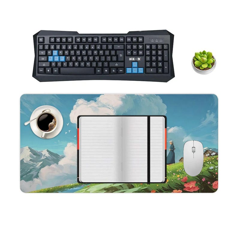 K&ouml;nnte beinhalten: Eine schwarze Computertastatur mit blauen Tasten und eine passende Maus, ein Mauspads mit Landschaftsdesign, eine Tasse Kaffee, ein Notizbuch und eine kleine Topf-Sukkulente. Das Mauspads zeigt eine malerische Illustration.