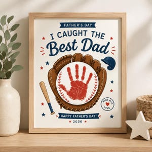 Può includere: Una stampa incorniciata con il testo FATHER'S DAY, I CAUGHT THE BEST DAD, e HAPPY FATHER'S DAY! 2026. Il design include un guantone da baseball marrone, una palla con un'impronta rossa, una mazza, un casco blu e stelle rosse e blu.
