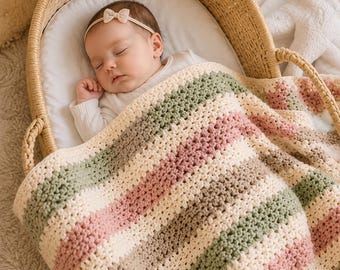 May include: A baby sleeping in a woven wicker bassinet, covered by a crocheted blanket featuring horizontal stripes in cream, sage green, and dusty rose. The baby wears a white long-sleeved top and a thin headband with a small bow detail.
