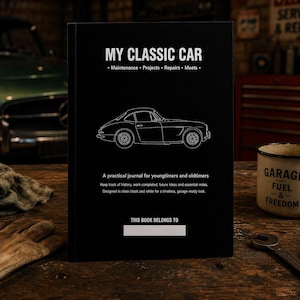 May include: A black journal titled "MY CLASSIC CAR" with a white line drawing of a vintage car. The journal includes sections for maintenance, projects, repairs, and meets. A vintage-style mug with "GARAGE FUEL & FREEDOM" is on the right.