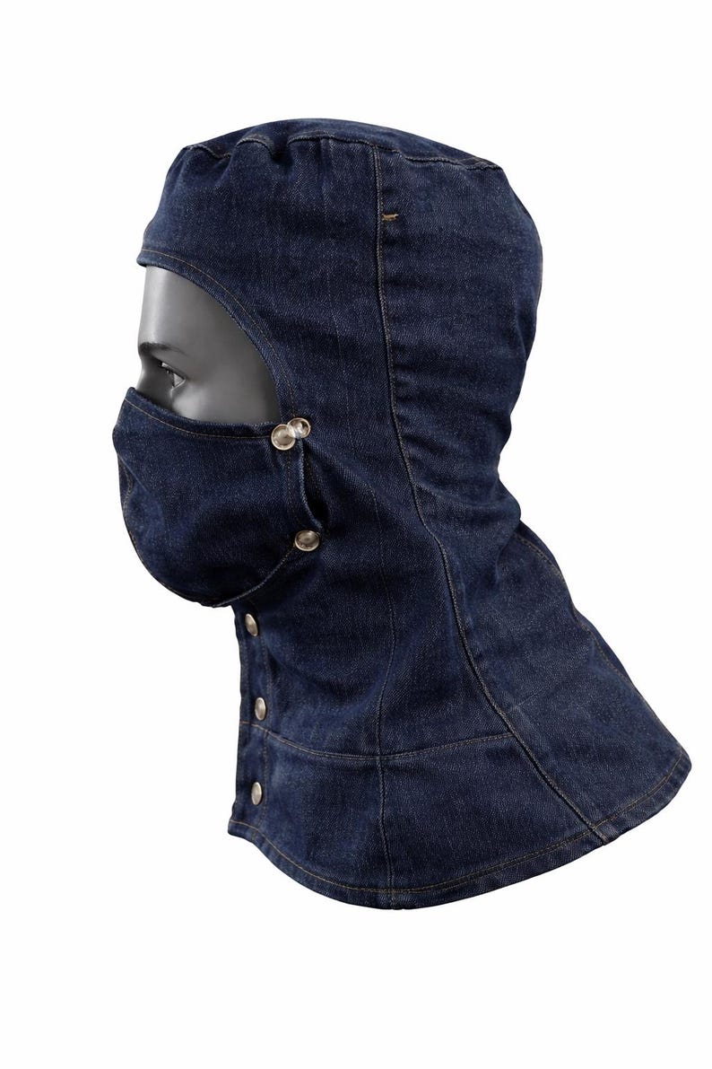Pu&ograve; includere: Un passamontagna in denim blu scuro con una copertura per il viso e una chiusura con bottoni. Il passamontagna copre la testa e il collo, con un'apertura per gli occhi. La copertura per il viso &egrave; fissata con bottoni argentati.