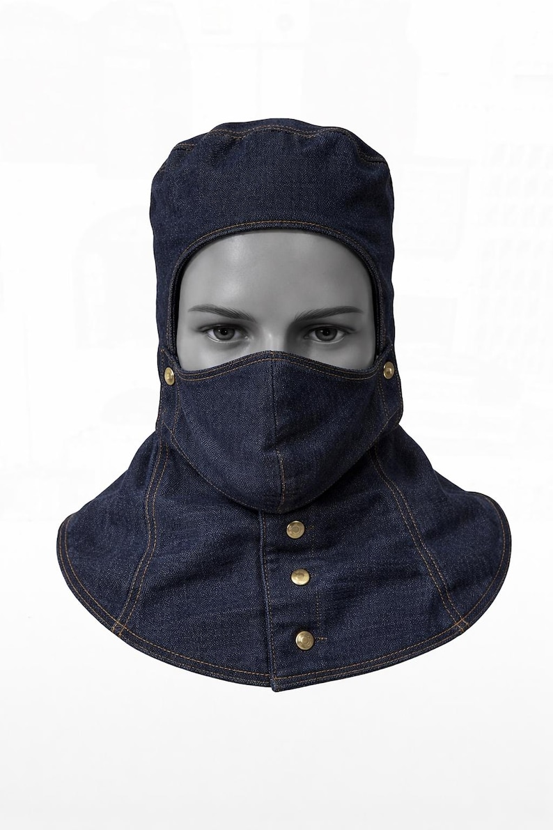 Pu&ograve; includere: Un passamontagna in denim blu scuro con una maschera facciale e un colletto integrati. Il passamontagna ha bottoni color oro e cuciture a vista. Il copricapo &egrave; progettato per proteggere il viso e il collo.