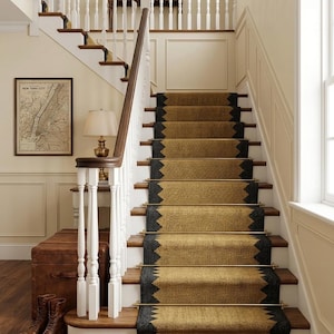 May include: A staircase with a woven runner in shades of gold and black. The stairs have wooden steps and white balusters. A map of New York City hangs on the wall, and a leather trunk and boots sit at the base of the stairs.