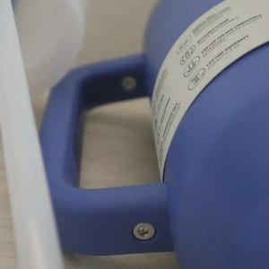 Puede incluir: Primer plano de un vaso azul con asa y pajita blanca. El vaso tiene un asa y una etiqueta blanca con texto. La pajita es blanca y est&aacute; colocada cerca del vaso. El vaso es de un material liso.